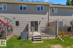 Rear exterior with beige horizontal siding and a ground-level wood deck - 