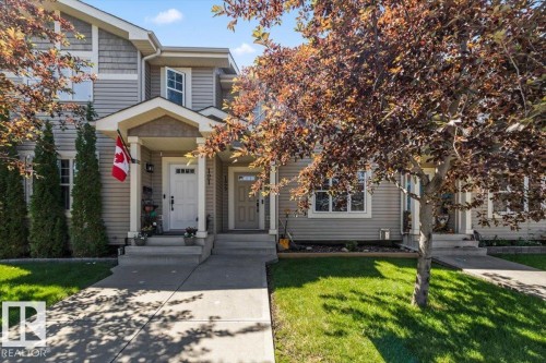 Front exterior featuring light-colored siding, a covered porch entrance, and a concrete walkway - 125 Birchwood Close, Devon, AB 