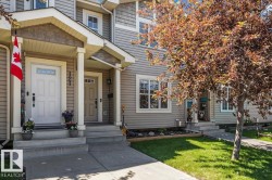 Townhome exterior featuring light gray siding, white trim, and a covered porch entry - 