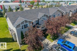 Modern townhome exterior featuring light gray siding, dark shingle roofing, and decorative gables with shingle accents - 