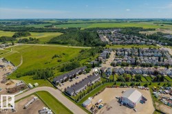 Aerial perspective showcasing the property within a residential development, bordered by expansive green spaces and fields - 