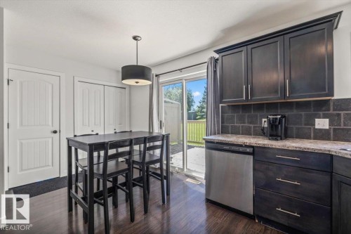 Kitchen area featuring dark wood-finish flooring, dark cabinetry with brushed nickel hardware, and a tile backsplash - 125 Birchwood Close, Devon, AB 