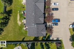 Multi-unit residential building featuring a dark shingle roof and individual rear patios - 