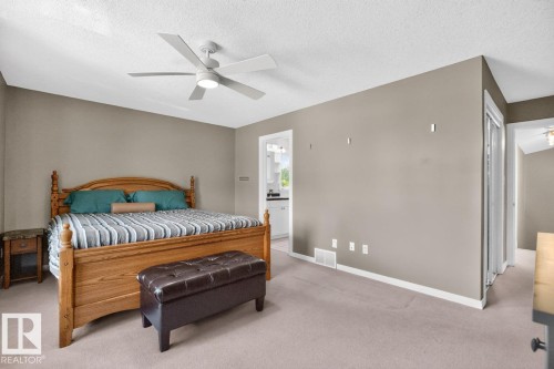 Carpeted bedroom featuring a ceiling fan with integrated lighting, neutral wall paint, and white baseboards - 619 Layton Crest, Edmonton, AB 