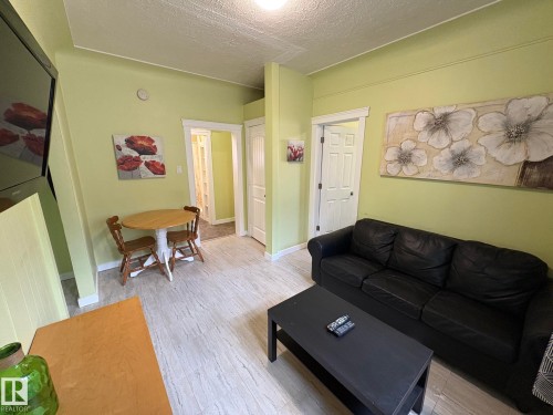 Open-concept living space featuring wood-finish flooring, light green wall paint, and white trim - 11511 101 Street, Edmonton, AB 