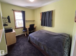 Bedroom featuring light green walls, a patterned dark carpet, and a window with a wood-finish frame - 