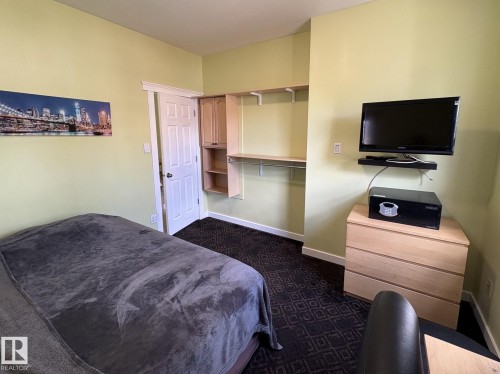 Room featuring light green wall paint, dark patterned carpet, and white trim - 11511 101 Street, Edmonton, AB 