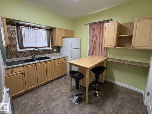 Kitchen featuring light wood-finish cabinetry and a mosaic tile backsplash - 11511 101 Street, Edmonton, AB 