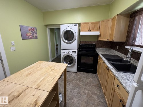Kitchen area featuring light wood-finish cabinetry, granite-style countertops, and a black double basin sink with a gooseneck faucet - 11511 101 Street, Edmonton, AB 