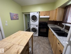 Kitchen area featuring light wood-finish cabinetry, granite-style countertops, and a black double basin sink with a gooseneck faucet - 