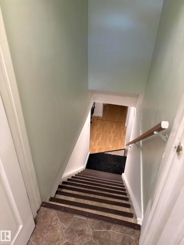 Stairwell with stone-look tile flooring at the top, leading down to wood-finish flooring - 11511 101 Street, Edmonton, AB 