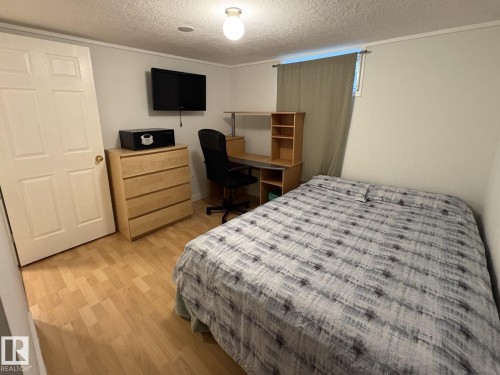 Bedroom featuring wood-finish flooring, a neutral wall color, and a window with natural light - 11511 101 Street, Edmonton, AB 