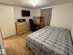 Bedroom featuring wood-finish flooring, a neutral wall color, and a window with natural light - 