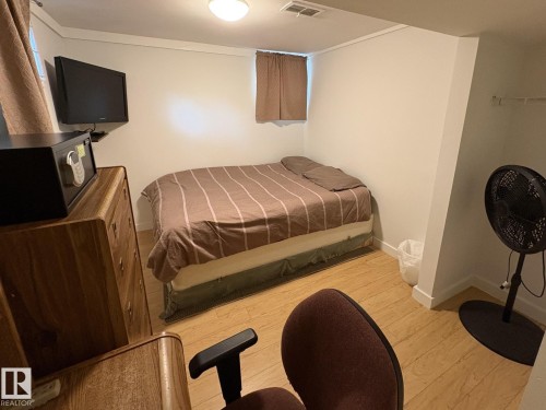 Compact interior space featuring wood-finish flooring and a wall-mounted television - 11511 101 Street, Edmonton, AB 