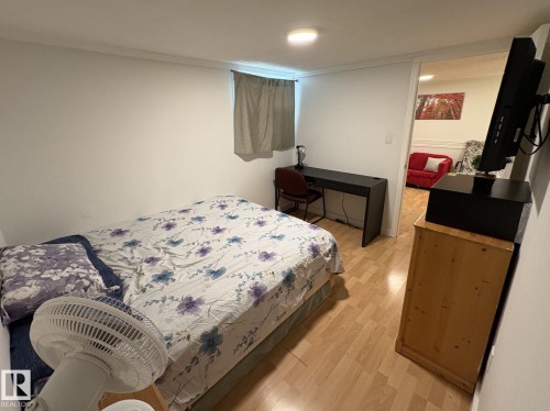 Bedroom featuring wood-finish flooring, a window with curtains, and a built-in ceiling light fixture - 11511 101 Street, Edmonton, AB 
