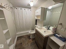 Bathroom featuring a single vanity with a rectangular sink, wood-finish cabinetry, and a large mirror - 