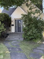 Front exterior with light-colored siding and a dark entry door featuring an oval glass insert - 