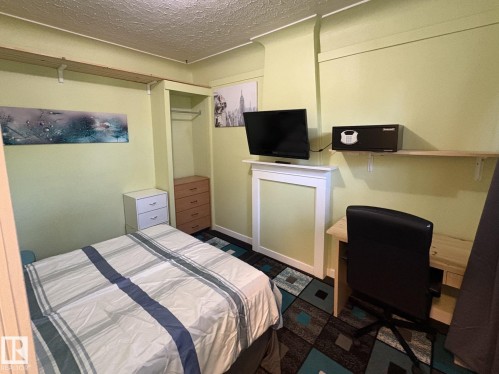 Room featuring light green walls, a patterned carpet, and a built-in closet with hanging rod and shelf - 11511 101 Street, Edmonton, AB 