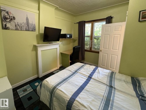 Interior room featuring a white paneled door, a window with dark wood trim, and light green walls - 11511 101 Street, Edmonton, AB 