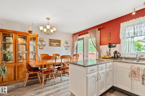 Kitchen and dining area featuring wood-finish flooring, white cabinetry with silver hardware, and a granite-style countertop - 30 Garden Valley Drive, Stony Plain, AB - Indoor