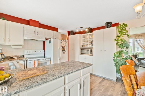 Kitchen featuring white cabinetry, stone-finish countertops, wood-finish flooring, and a built-in microwave - 30 Garden Valley Drive, Stony Plain, AB - Indoor Photo Showing Kitchen