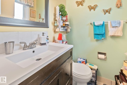 White integrated sink with a brushed nickel faucet, set into a dark wood-finish vanity with square knobs - 30 Garden Valley Drive, Stony Plain, AB - Indoor Photo Showing Bathroom