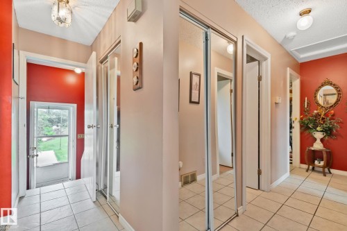 Hallway featuring tile flooring, mirrored closet doors, white trim, and a glass-paneled exterior door - 30 Garden Valley Drive, Stony Plain, AB - Indoor Photo Showing Other Room