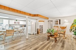 Open-concept lower level featuring wood-finish flooring, white cabinetry, recessed lighting, and a drop ceiling - 