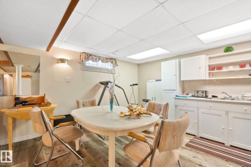 Versatile space featuring wood-finish flooring, drop ceiling with integrated lighting, a functional kitchenette with white cabinetry, and a window with valance - 30 Garden Valley Drive, Stony Plain, AB - Indoor