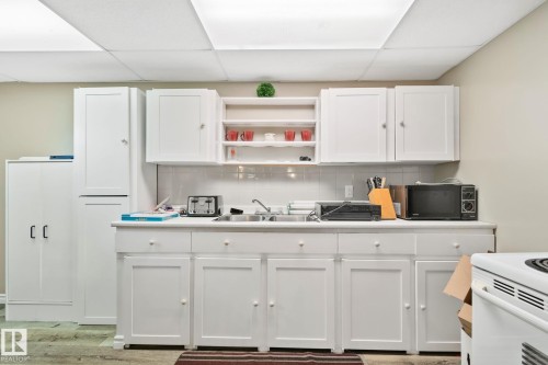 Kitchenette featuring white cabinetry, a single basin sink, white subway tile backsplash, and overhead fluorescent lighting - 30 Garden Valley Drive, Stony Plain, AB - Indoor Photo Showing Kitchen With Double Sink