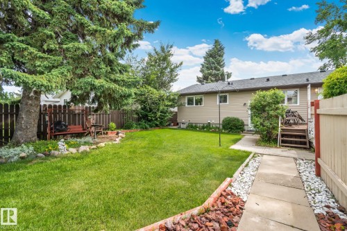 Expansive backyard featuring a manicured lawn, established trees, and a concrete pathway - 30 Garden Valley Drive, Stony Plain, AB - Outdoor