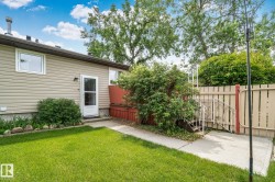 Rear exterior featuring tan horizontal siding and a white door with a glass panel - 