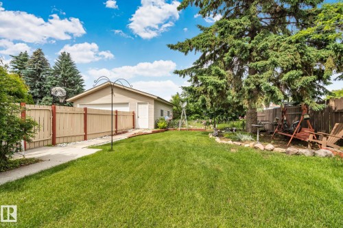 Spacious backyard featuring a manicured lawn, paved walkway, and a detached two-car garage with siding exterior - 30 Garden Valley Drive, Stony Plain, AB - Outdoor