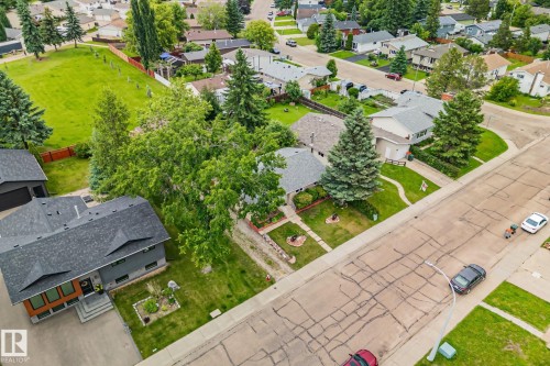 Modern-style residence featuring a dark gray exterior with wood-finish paneling, a multi-gabled shingled roof, a concrete driveway, and an attached garage - 30 Garden Valley Drive, Stony Plain, AB - Outdoor With View