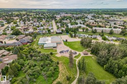 Aerial perspective showcasing a residential neighborhood with a variety of housing styles, established green spaces, and a public facility - 