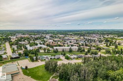 Expansive aerial perspective showcasing a community with diverse residential architecture, mature tree-lined streets, and open green spaces - 