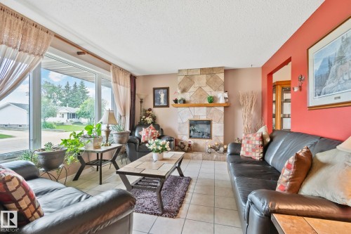 Spacious living area featuring a prominent stone-clad fireplace with a natural wood mantel - 30 Garden Valley Drive, Stony Plain, AB - Indoor Photo Showing Living Room With Fireplace