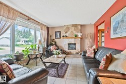Spacious living area featuring a prominent stone-clad fireplace with a natural wood mantel - 