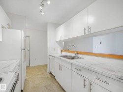 Contemporary kitchen featuring white cabinetry and light-toned countertops - 