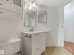 Bathroom with a white vanity featuring a single basin sink and brushed nickel faucet - 