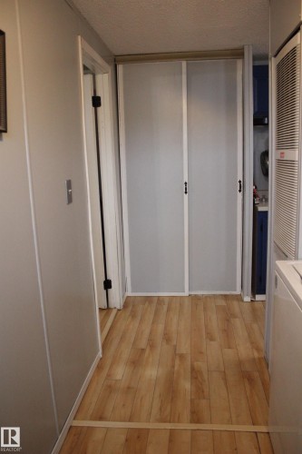 Hallway featuring wood-finish flooring, light grey walls, and a textured ceiling - 4839 49 Avenue, Chipman, AB 