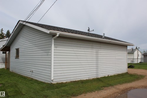 Detached garage featuring horizontal siding, a gabled roof with dark shingles, and white gutters - 4839 49 Avenue, Chipman, AB 