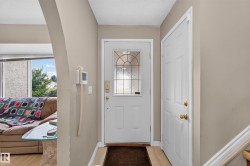 Inviting entryway featuring a white paneled front door with decorative glass inserts, wood-finish flooring, and light neutral wall paint - 