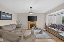 Living area featuring wood-finish flooring, a fireplace with a wood mantle, and a bay window - 