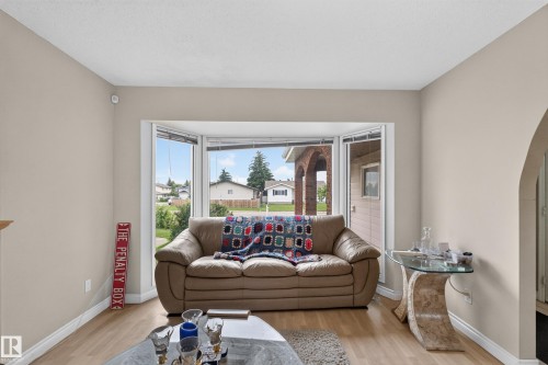 Living area featuring a prominent bay window, light wood-finish flooring, and an arched doorway - 3841 62 Street, Edmonton, AB 