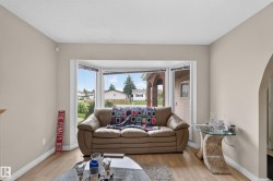 Living area featuring a prominent bay window, light wood-finish flooring, and an arched doorway - 