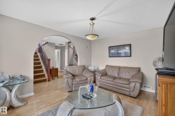 Living area featuring wood-finish flooring, a contemporary ceiling fixture, and neutral wall tones - 