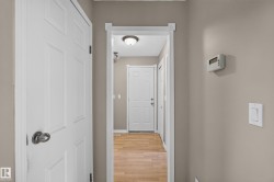 Interior corridor featuring neutral wall tones, white trim, and wood-finish flooring - 