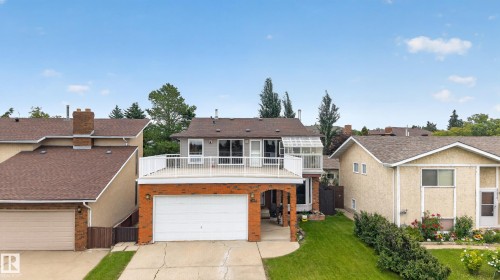 Split-level residence featuring a brick and stucco exterior, an elevated deck with white railings, and an attached two-car garage - 3841 62 Street, Edmonton, AB 