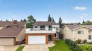 Split-level residence featuring a brick and stucco exterior, an elevated deck with white railings, and an attached two-car garage - 3841 62 Street, Edmonton, AB 